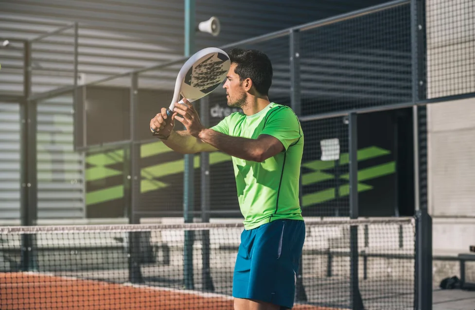 Un jugador de pádel realizando un golpe de preparación en una pista de pádel, con un fondo moderno y deportivo.