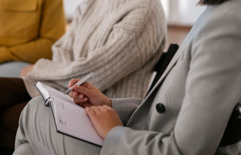 Grupo atendido por una psicóloga tomando notas durante la terapia, ejemplo de la labor de psicólogos en Donostia