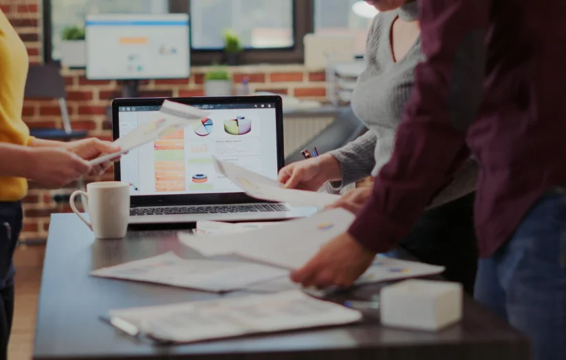 Equipo de consultores de marketing en Bilbao analizando gráficos y preparando informes durante una reunión de trabajo