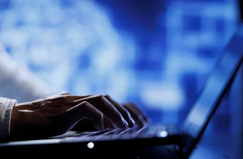 Manos tecleando en portátil con fondo tecnológico, ilustrando el trabajo técnico de las empresas de ciberseguridad en Argentina