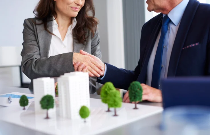 Asesores inmobiliarios cerrando un acuerdo con apretón de manos en una oficina